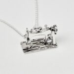 a silver necklace with a sewing machine