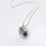 a silver ball necklace on a white background