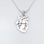 a silver heart necklace with a drawing on it