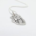 a silver heart necklace on a white background