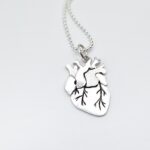 a silver heart necklace with a drawing of a human heart