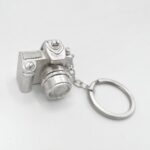 a silver key chain with a camera shaped object