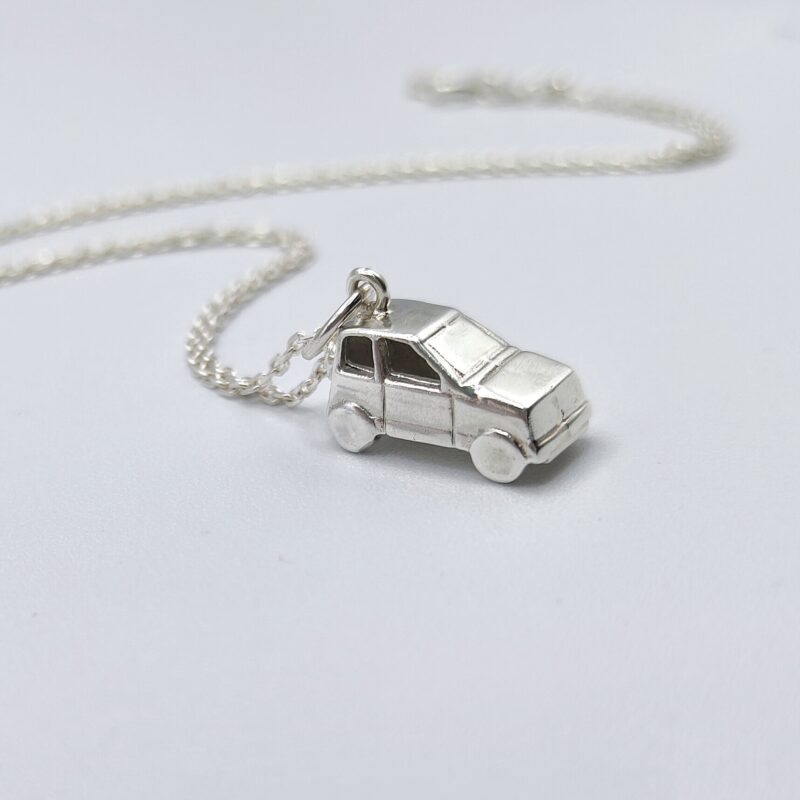 a silver car necklace on a white surface